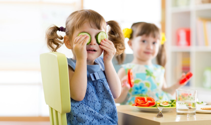 Kind das sich Gurkenscheiben vor die Augen hält